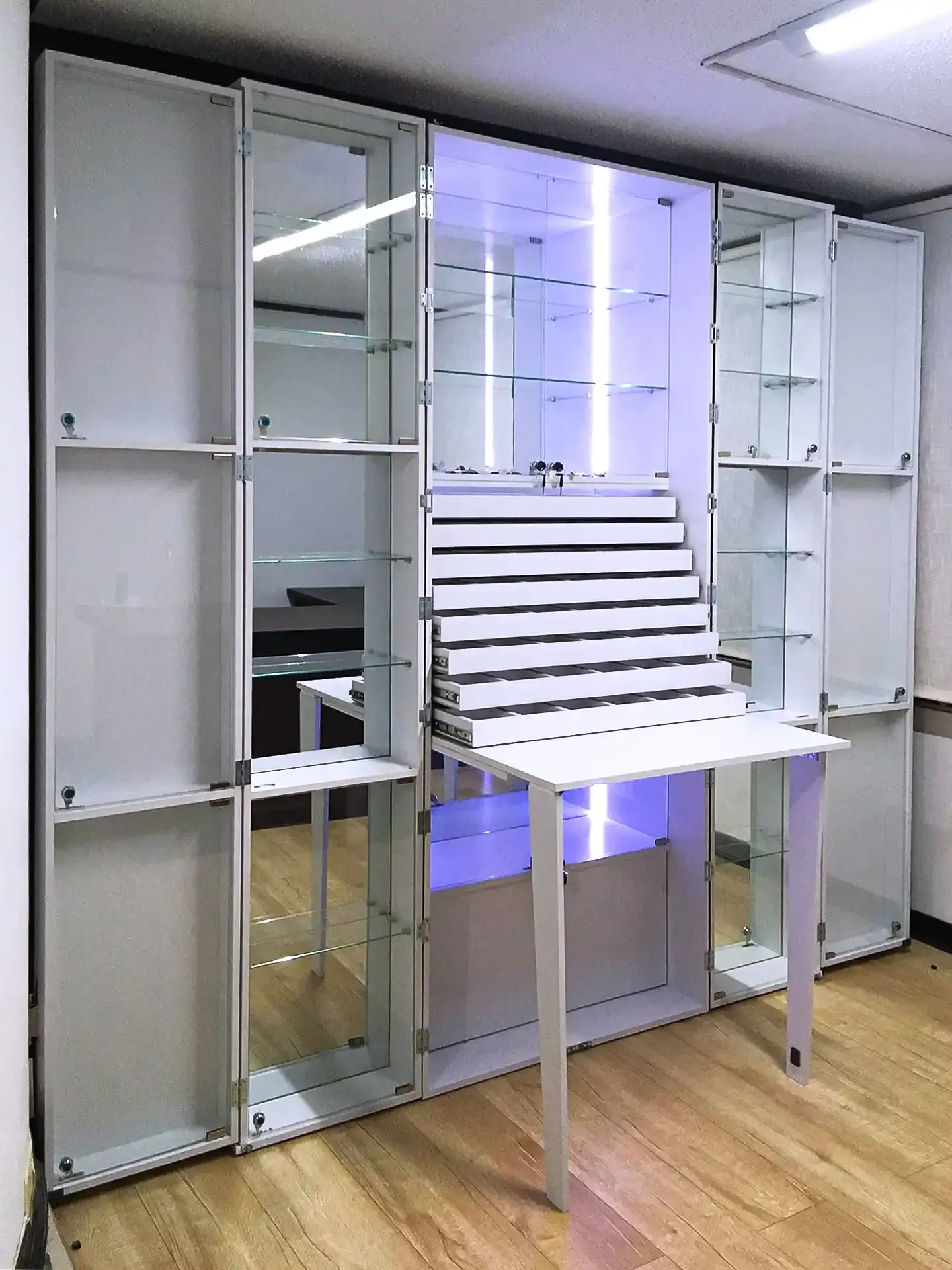 Mueble comercial con vitrinas de vidrio, compartimientos de exhibición y espacio de almacenamiento.