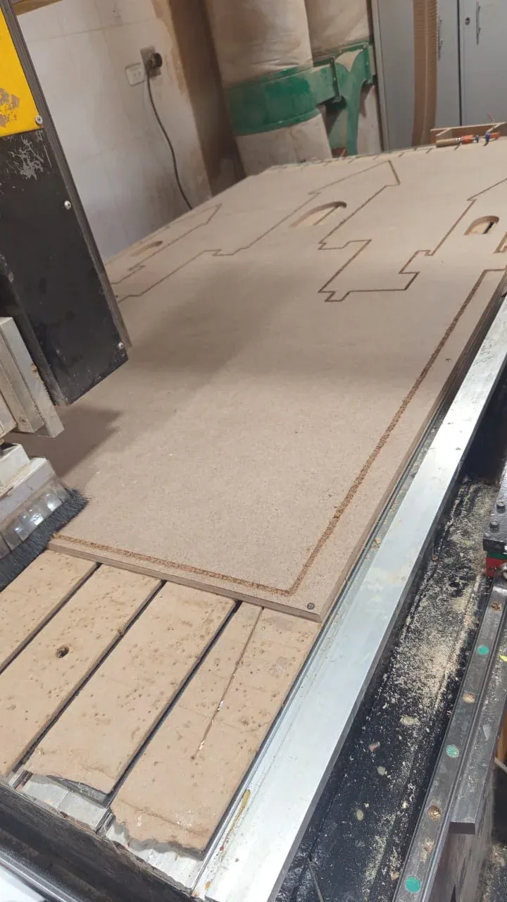 Tablero de MDF con piezas de contorno y calados mecanizados sobre la mesa CNC
